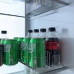 Drink pusher installed in refrigerator to organize mixed beverage cans.