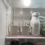 Close-up of shelf pusher track organizing retail beverage cans.