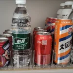 Push-feed shelf organizer used for aligning energy drinks inside fridge.
